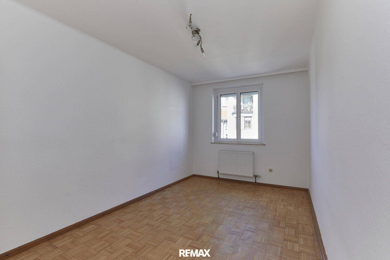 Helles, leeres Zimmer mit Parkettboden und einem Fenster, vielseitig nutzbar als Schlaf- oder Arbeitszimmer.