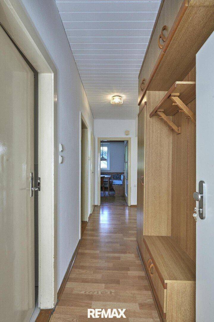 Langer Flur mit praktischen Einbauschränken und Holzvertäfelung, der zu weiteren Räumen führt.