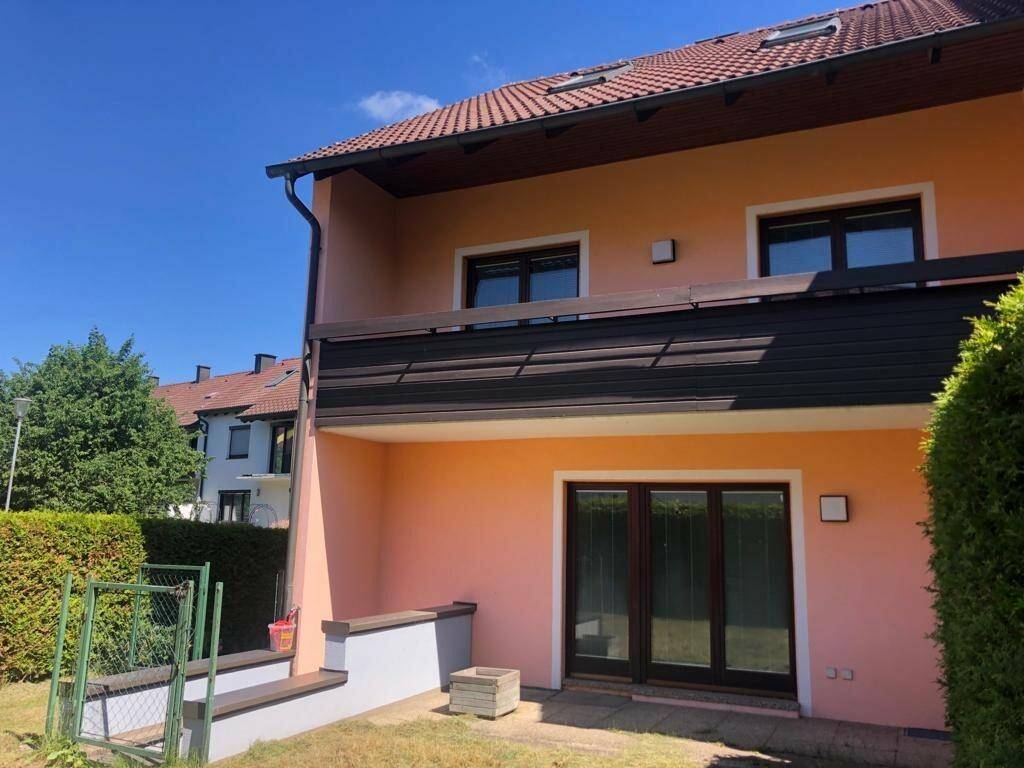 Rückseite des Hauses mit Terrasse im Erdgeschoss und Balkon im Obergeschoss.