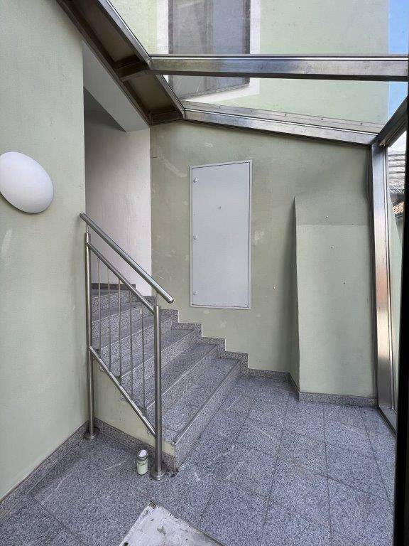 Heller Treppenaufgang mit Glasdach und Metallgeländer, führt zu den oberen Etagen.