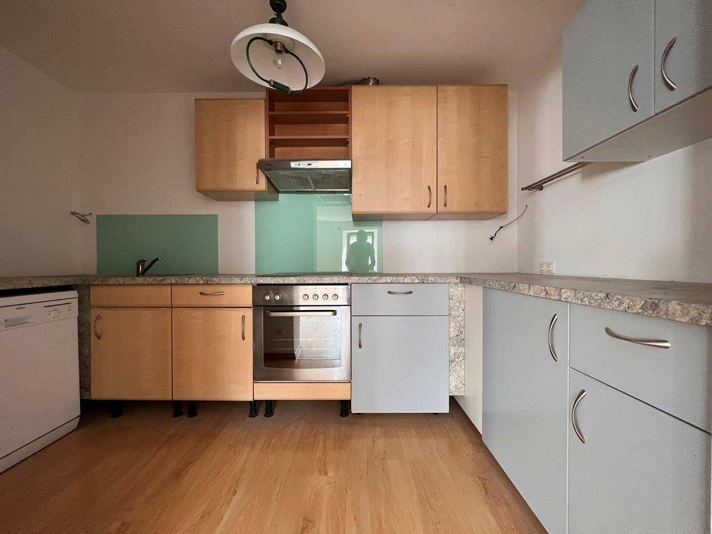 Funktionale Küche mit hellen Holzschränken, integriertem Backofen und Spülmaschine.