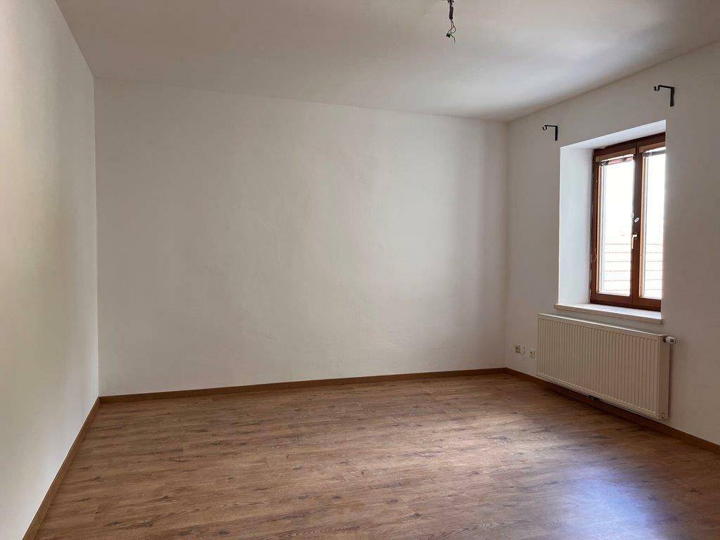 Heller Raum mit Laminatboden und Heizkörper unter dem Fenster, bereit zur Einrichtung.