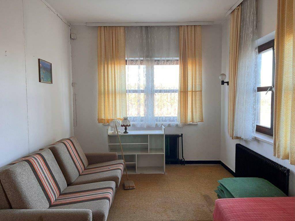Schlafzimmer mit Sofa, Fenster und Heizkörper, ausgestattet mit einfachen Möbeln.