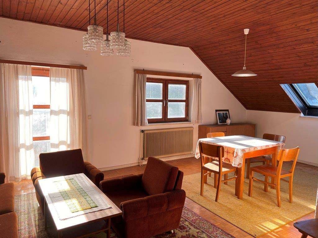 Gemütlicher Wohn-Essbereich im Dachgeschoss mit Holzdecke, Dachfenster und Blick nach draußen.