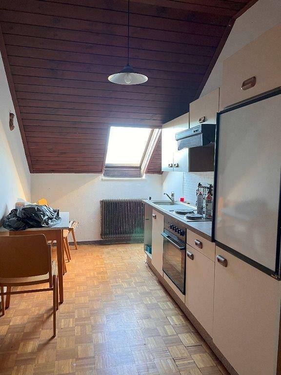 Kleine Küche im Dachgeschoss mit Holzdecke, Dachfenster und einfacher Küchenzeile.