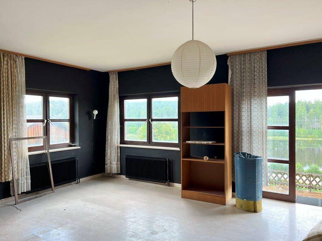 Heller Wohnraum mit dunklen Wänden, Zugang zum Balkon und weitem Blick auf den See.