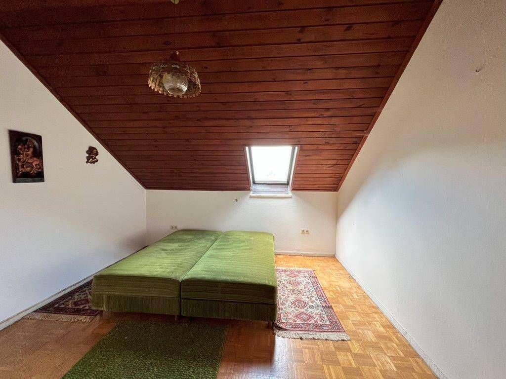 Schlafzimmer im Dachgeschoss mit Holzdecke, Dachfenster und einem grünen Bett.