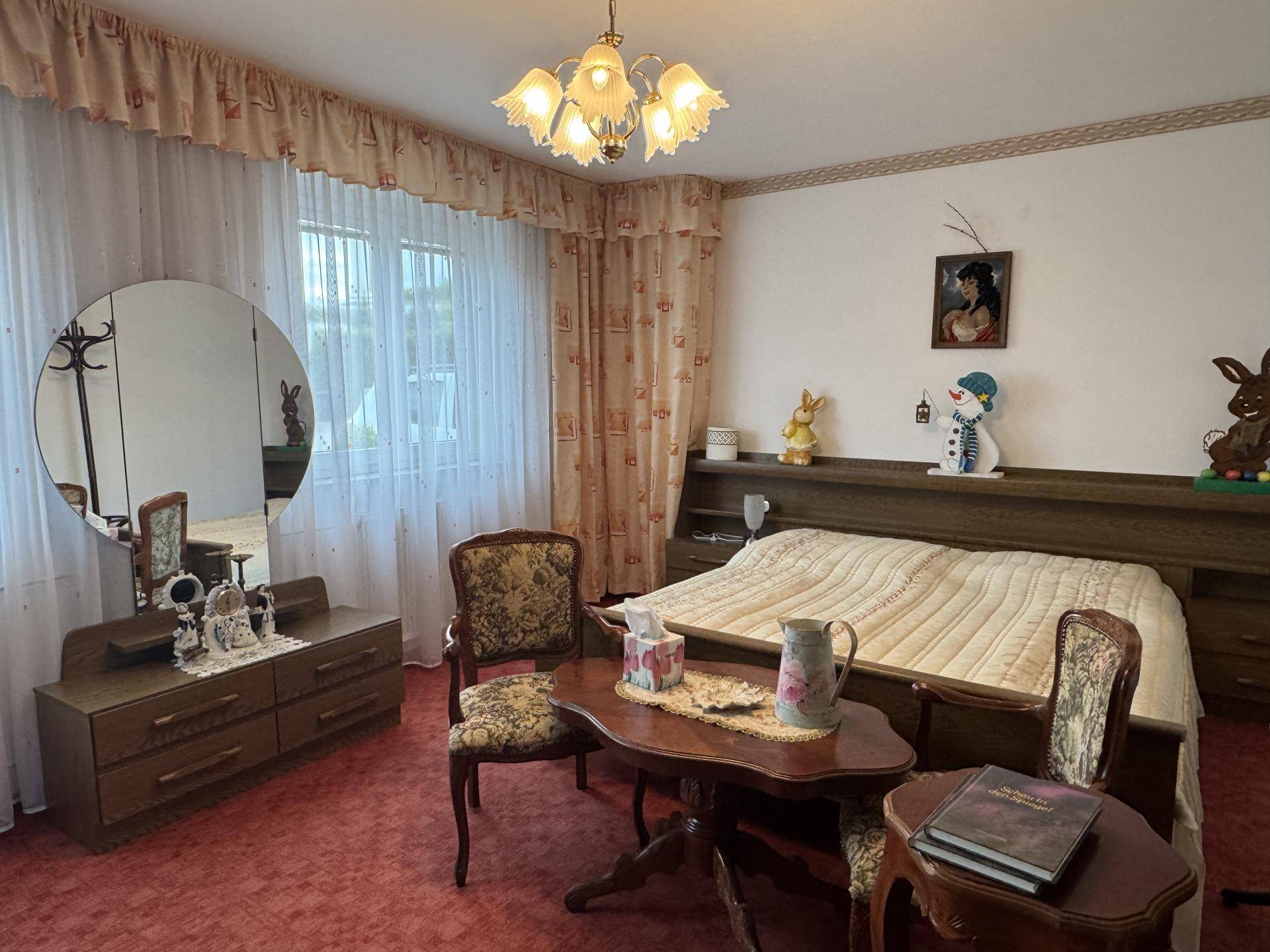 Gemütliches Schlafzimmer mit Doppelbett, Teppichboden und Vintage-Möbeln.