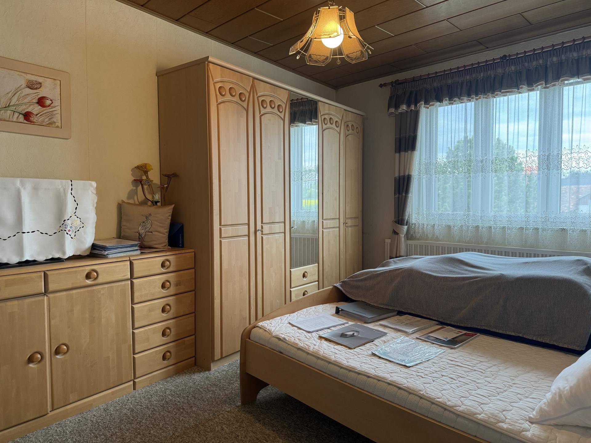 Schlafzimmer mit Holzdecke, Teppichboden und hellem Holzschrank.