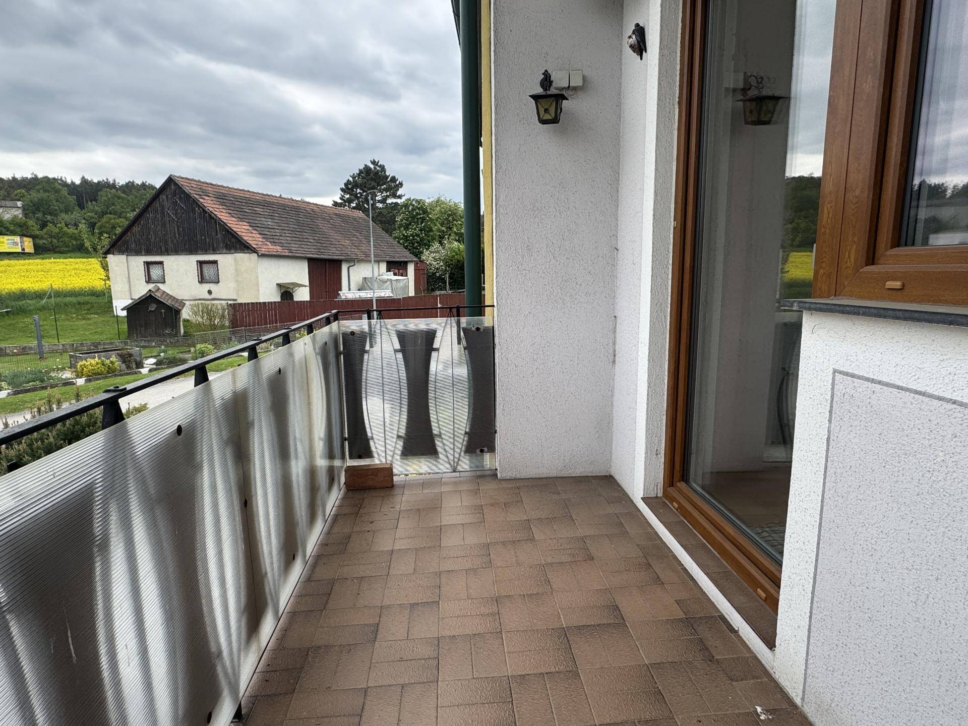 Kleiner Balkon mit Fliesenboden und Blick auf die ländliche Umgebung.