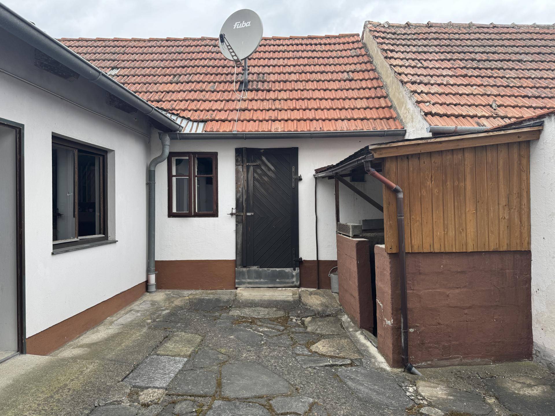 Rustikaler Innenhof mit Steinplatten und einem kleinen Holzschuppen.