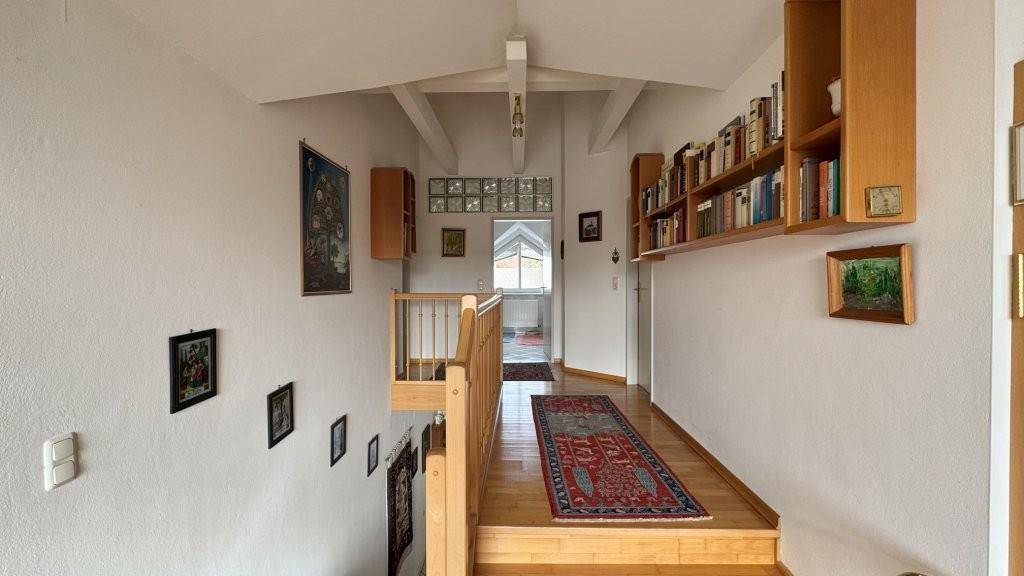 Oberer Flur mit Holzgeländer, Bücherregalen und Blick auf den Dachbodenbereich.