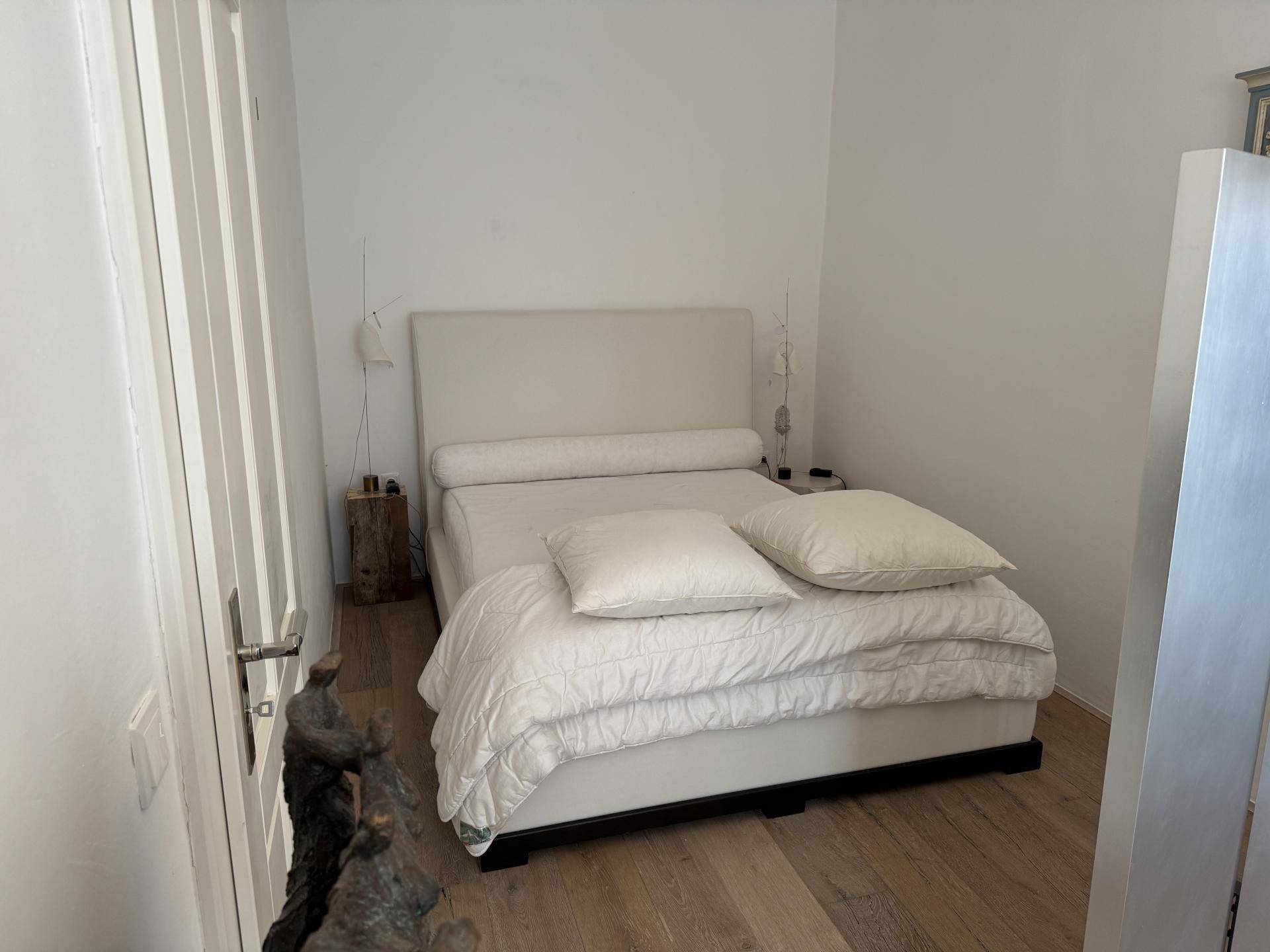 Helles Schlafzimmer mit Holzboden und minimalistischer Einrichtung.