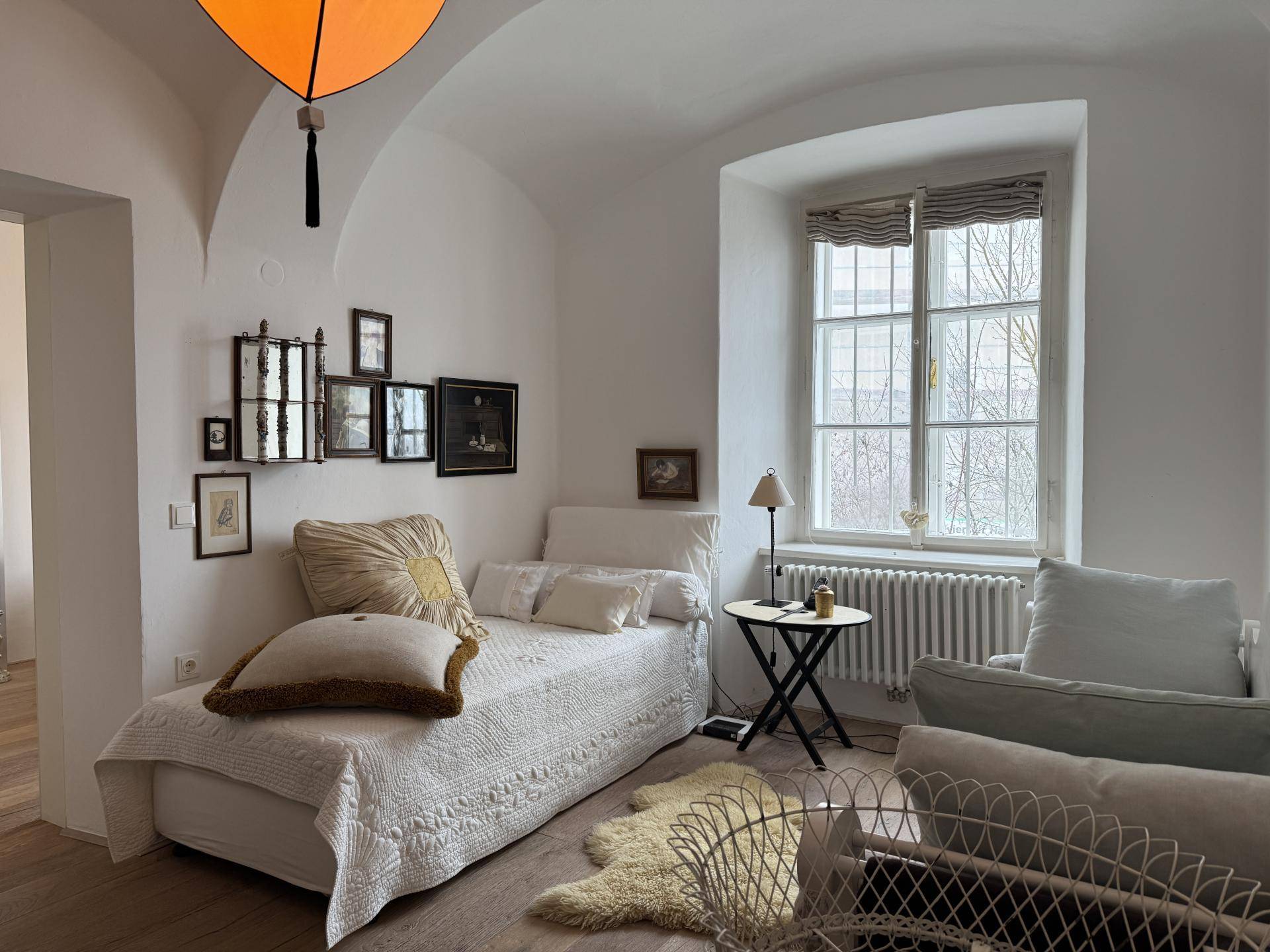 Gemütliches Schlafzimmer mit Holzboden, gewölbter Decke und Fenster mit Blick ins Grüne.