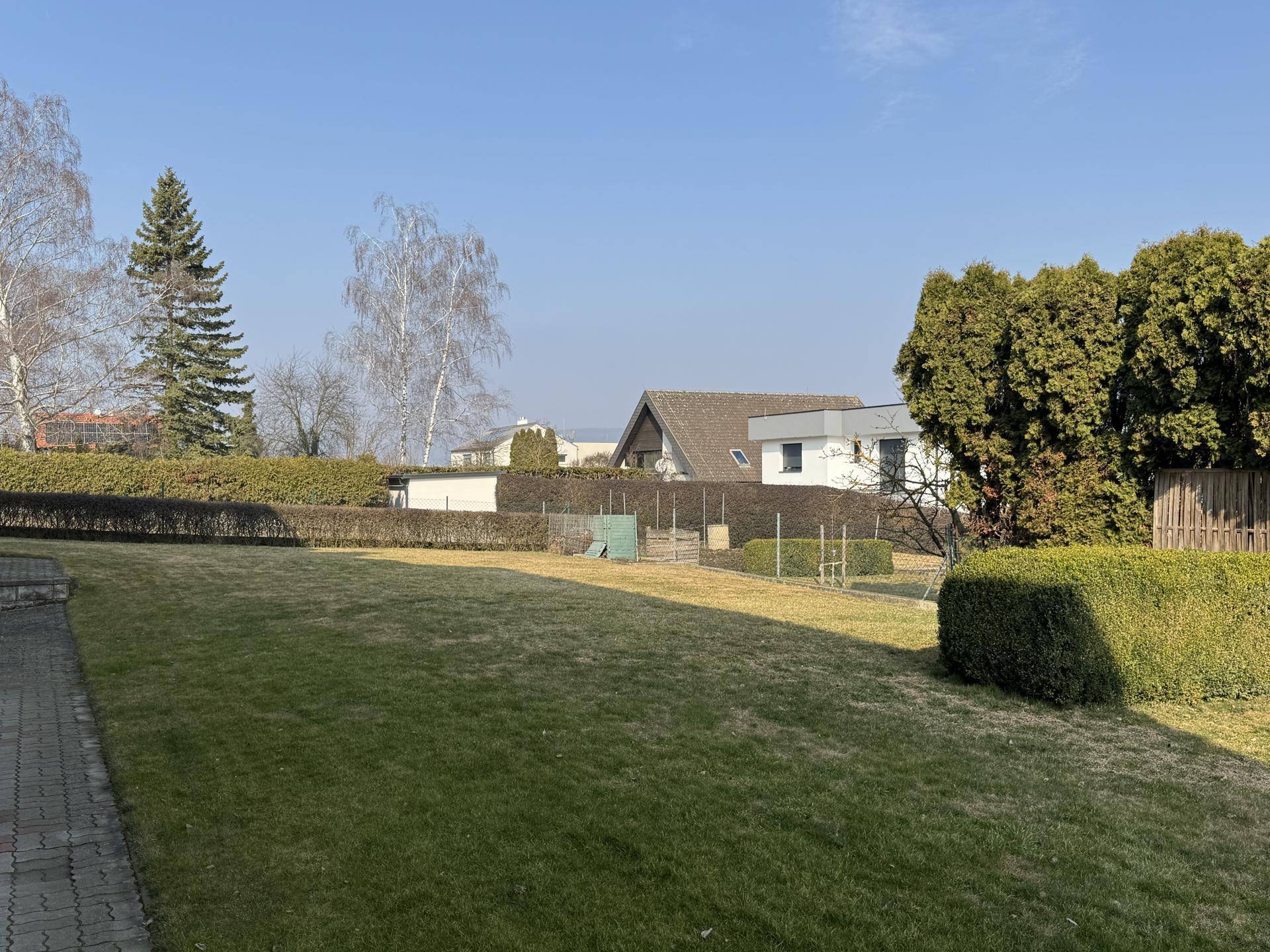 Weitläufiger Gartenbereich mit gepflegtem Rasen, hohen Hecken und altem Baumbestand.