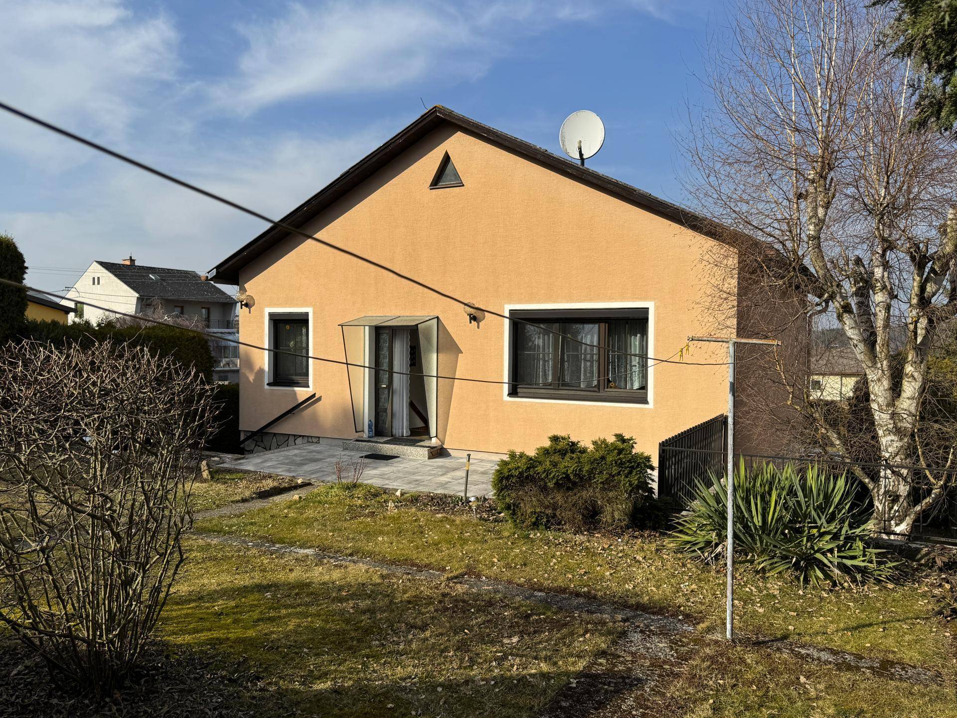 Rückansicht des Hauses mit Gartenbereich und Satellitenschüssel am Dach.