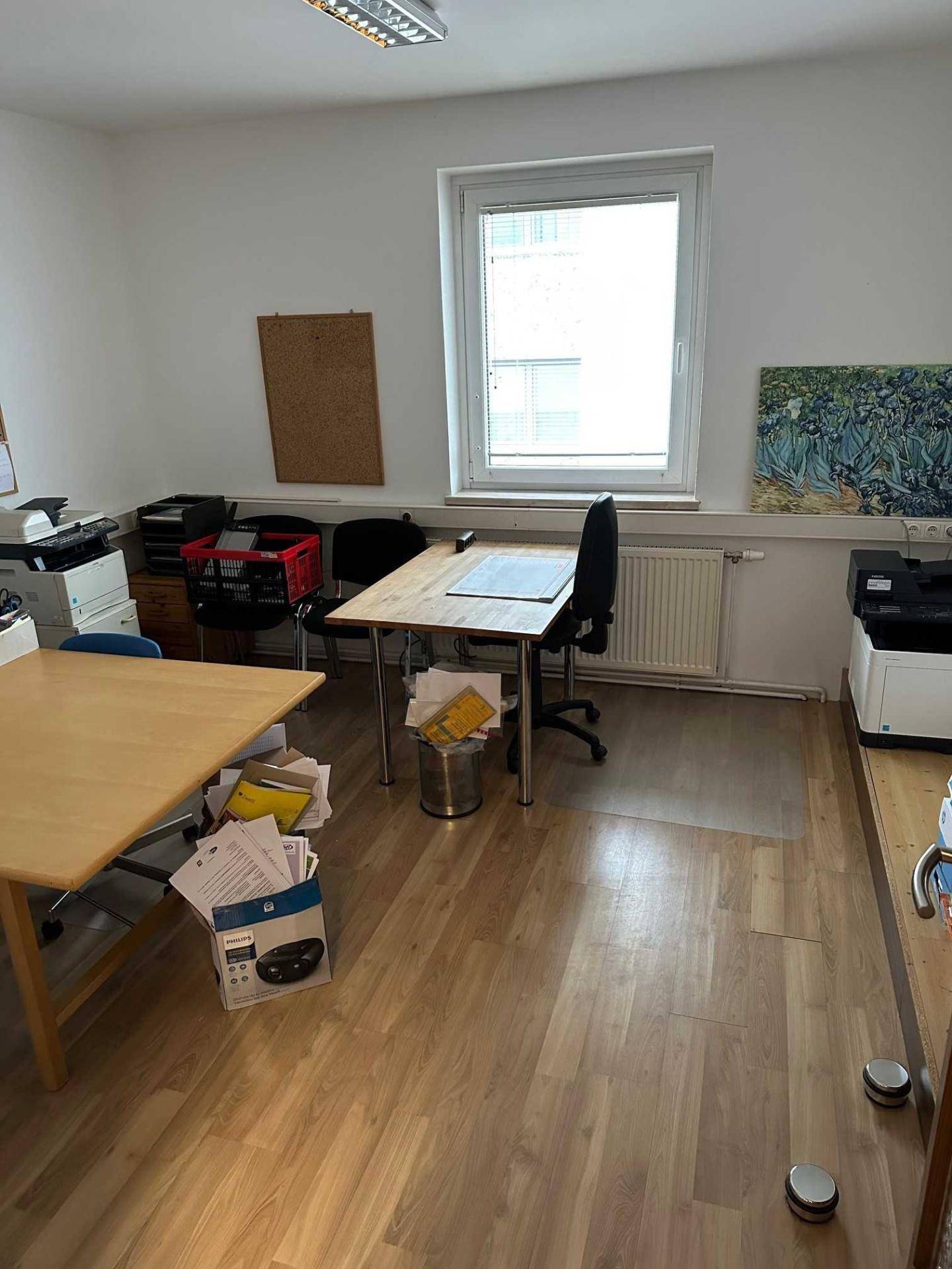Helles Büro mit zwei Schreibtischen, Bürostühlen und Druckern, ausgestattet mit Laminatboden.