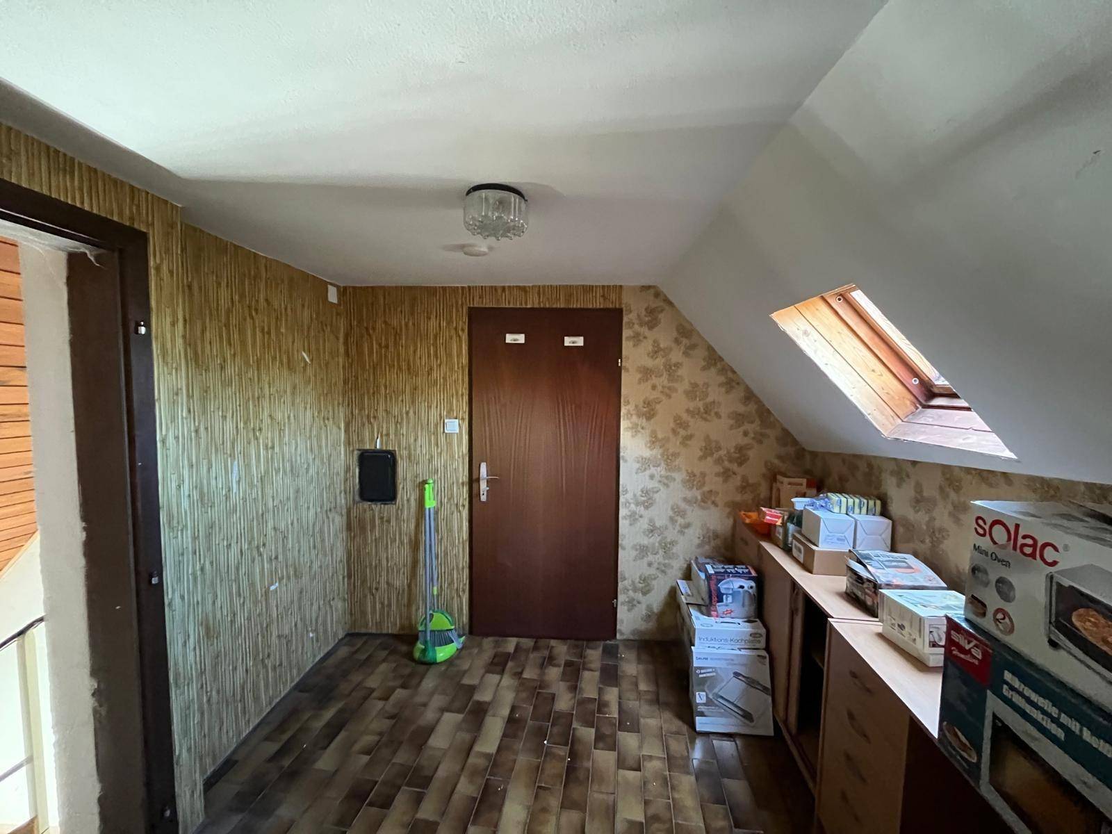 Dachgeschossflur mit schrägen Wänden, Dachfenster und gemusterten Tapeten.
