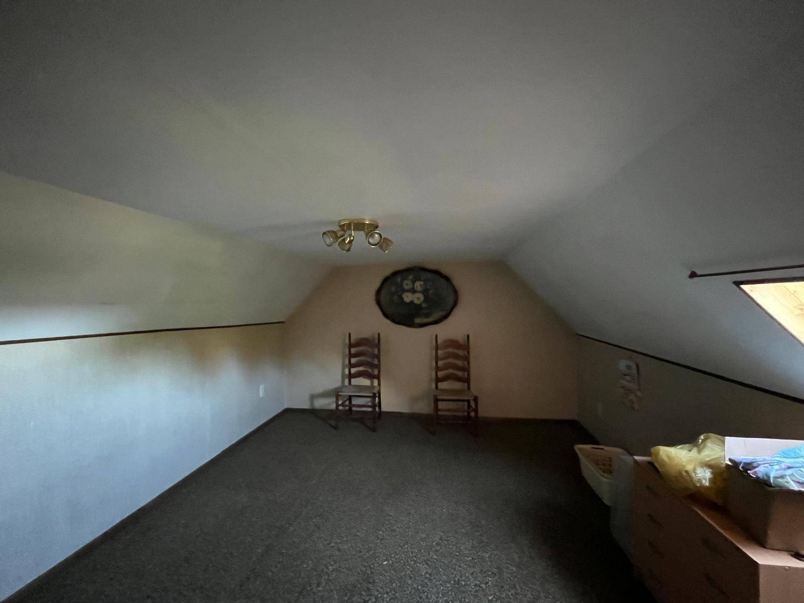 Dachgeschosszimmer mit Teppichboden und schrägen Wänden, bereit zur individuellen Gestaltung.