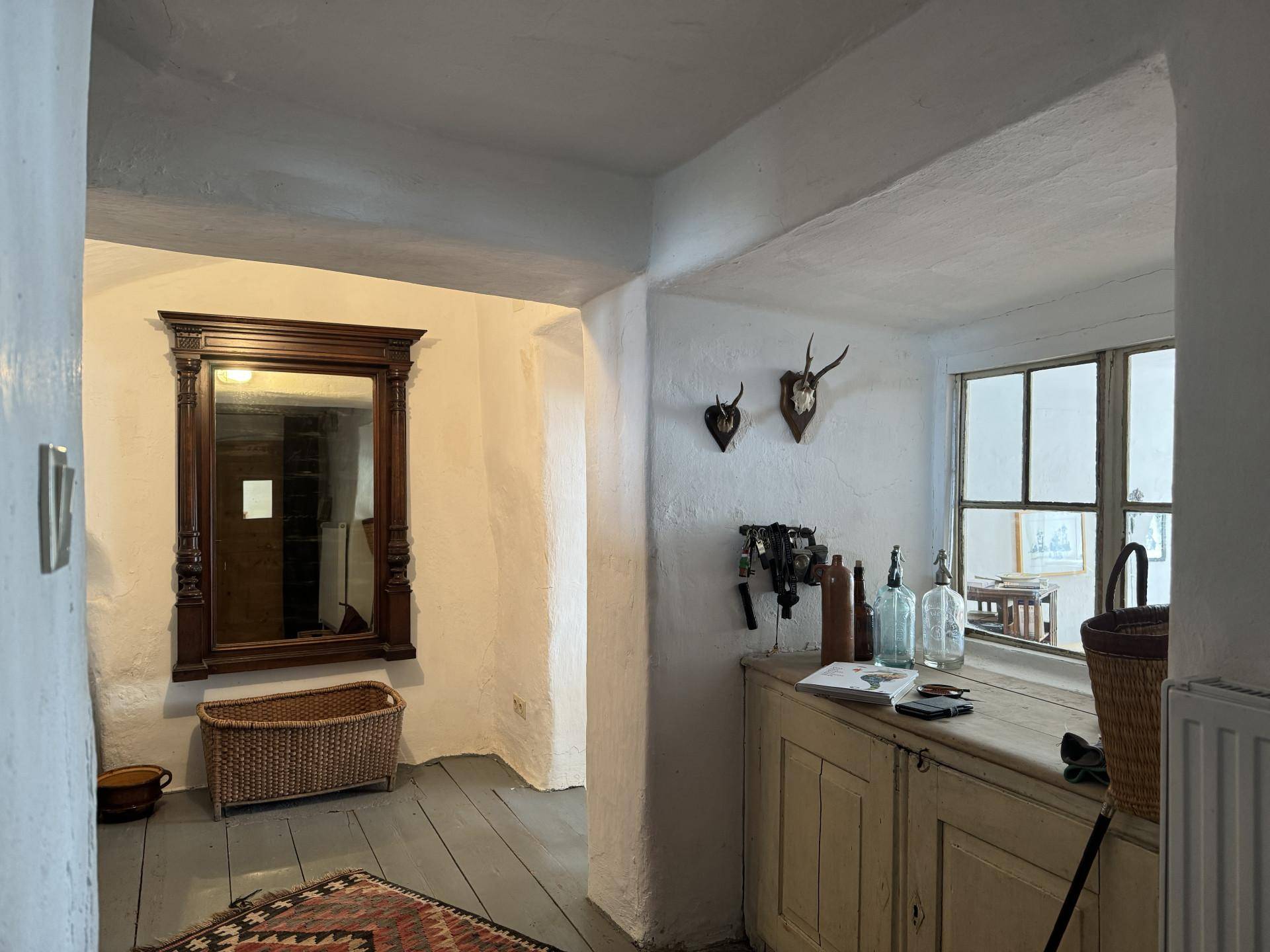 Gemütlicher Flur mit Holzboden, einem großen Spiegel und traditionellen Jagdtrophäen an der Wand.
