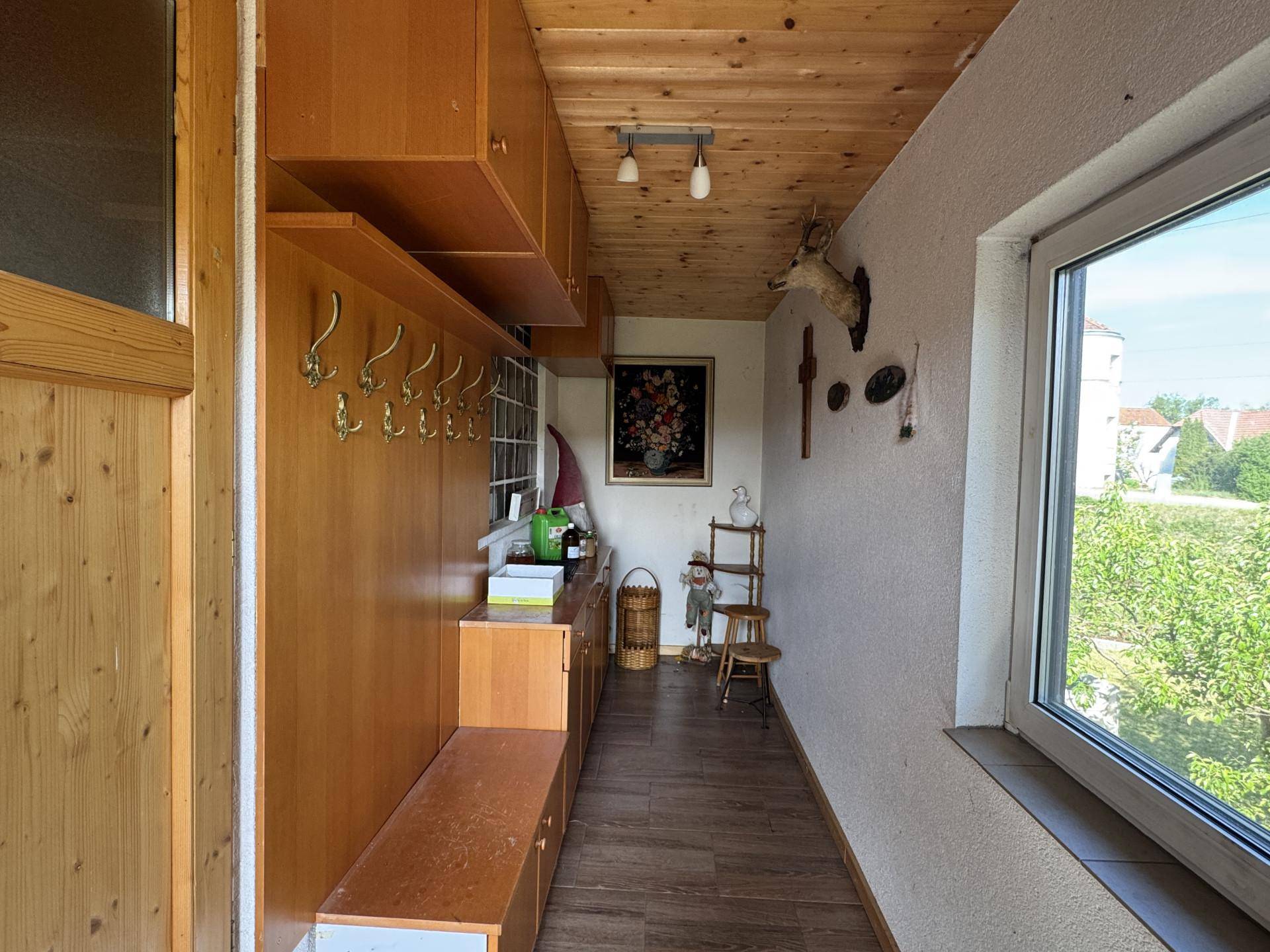 Gemütlicher Flur mit Holzvertäfelung, Garderobe und Fenster mit Blick ins Grüne.