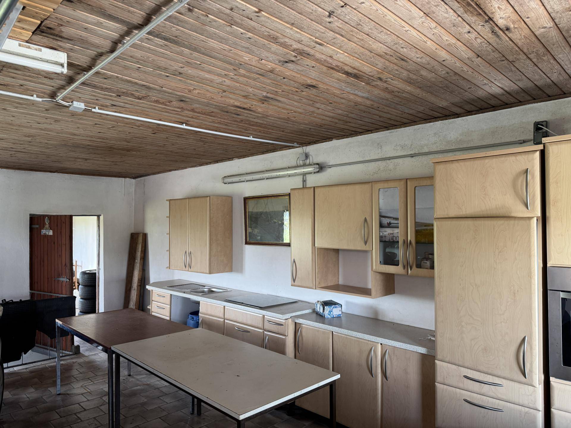 Funktionaler Raum mit Holzküche, Arbeitsplatten und Holzbalkendecke, ideal als Werkstatt oder Nebenküche.