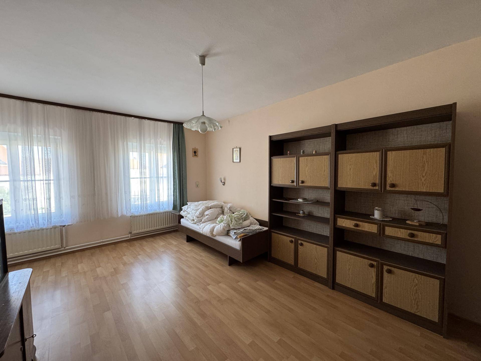 Helles Schlafzimmer mit Laminatboden, Einzelbett und großen Schränken an der Wand.