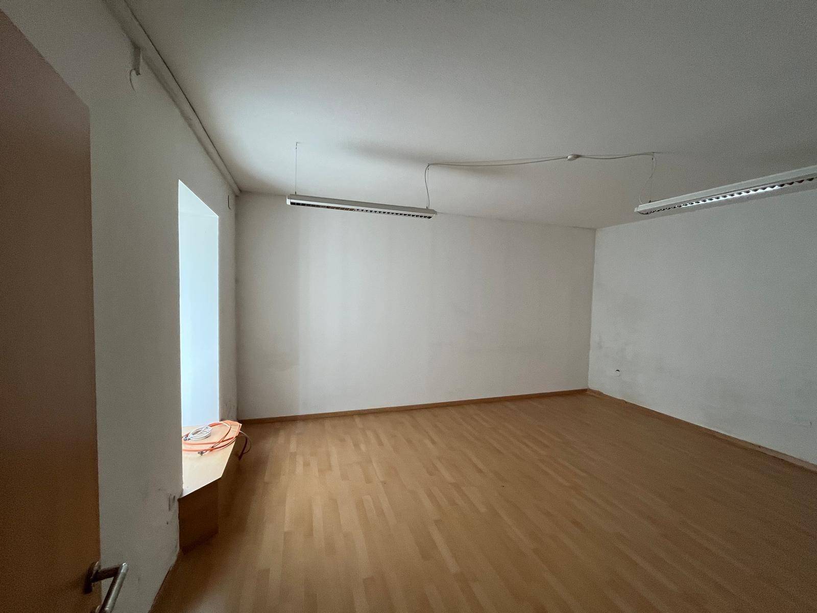 Heller Raum mit Parkettboden und großen Fenstern, ideal für Wohnzwecke.