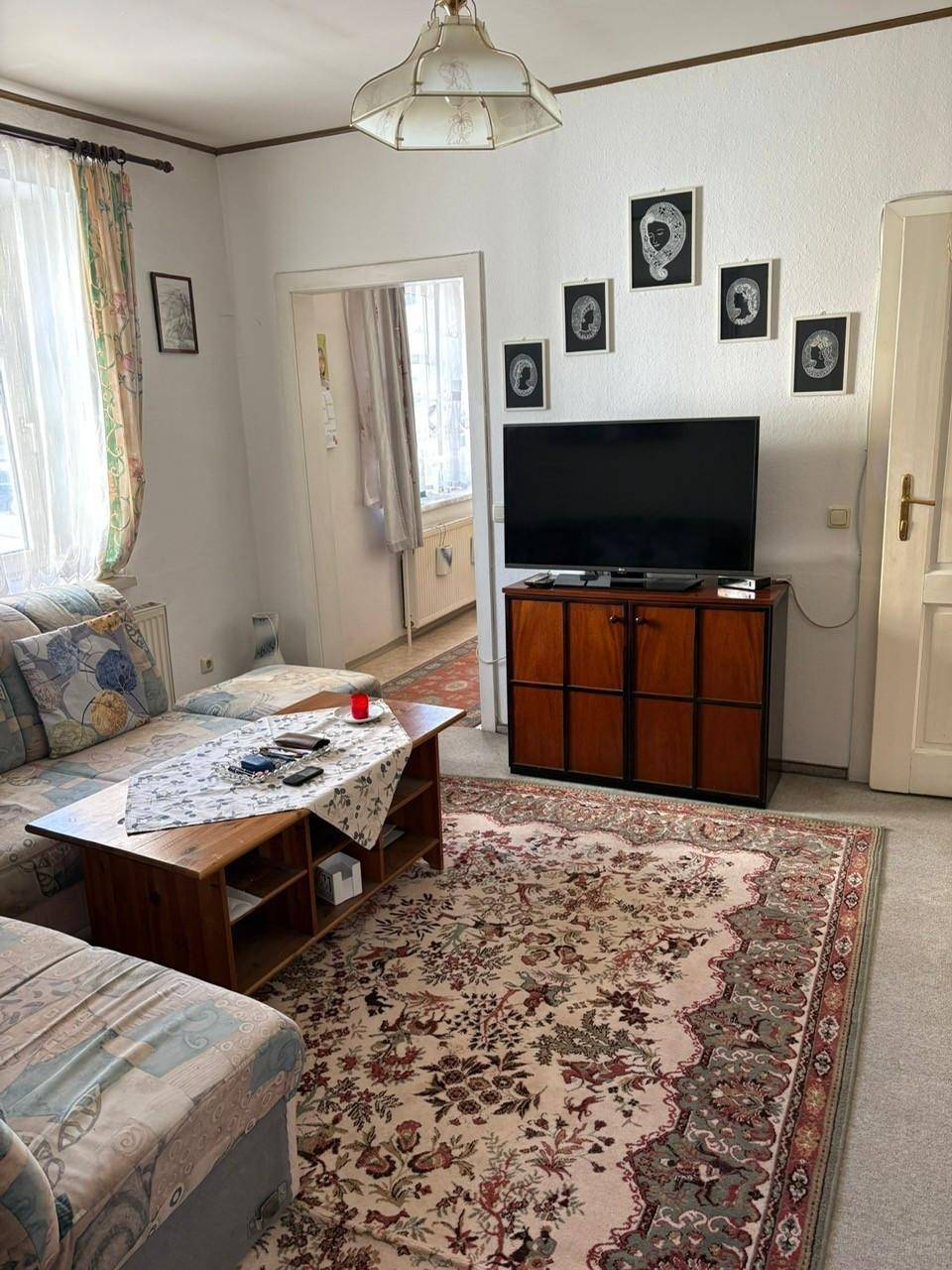 Gemütliches Wohnzimmer mit Teppichboden, Sofa, Couchtisch und Fernseher.