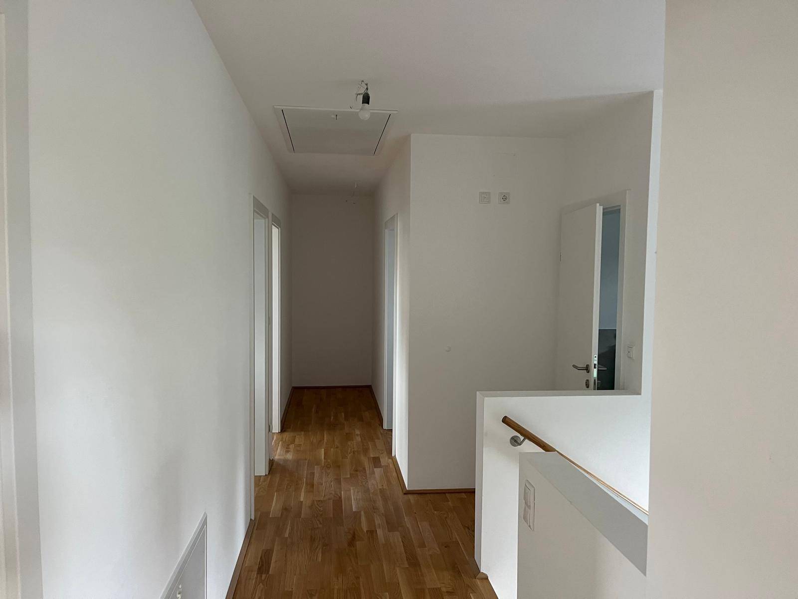 Heller Flur im Obergeschoss mit Holzparkettboden und Zugang zu weiteren Räumen.