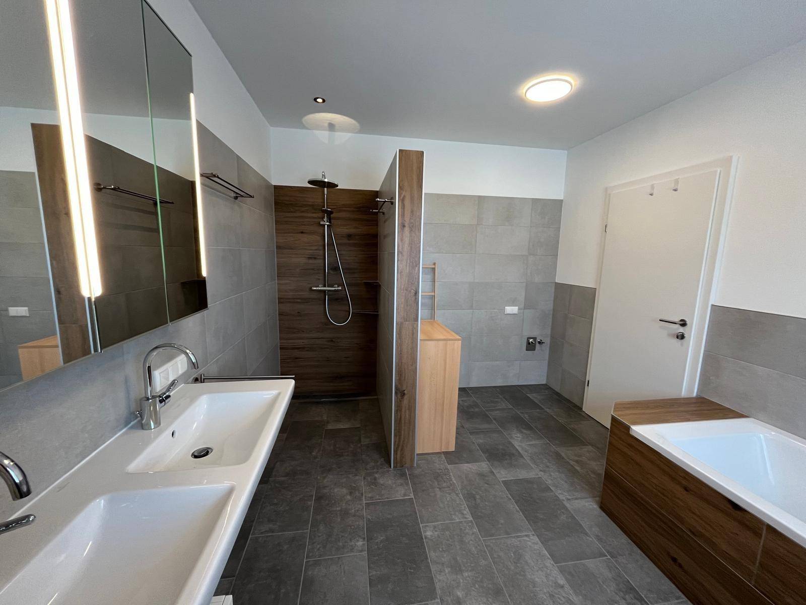 Modernes Badezimmer mit Doppelwaschbecken, großer Dusche und Badewanne.