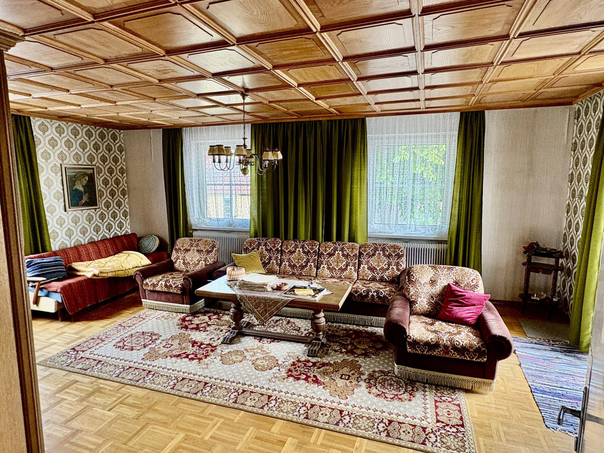 Klassisches Wohnzimmer mit einer verzierten Kassettendecke, traditionellen Möbeln und gemusterten Tapeten.