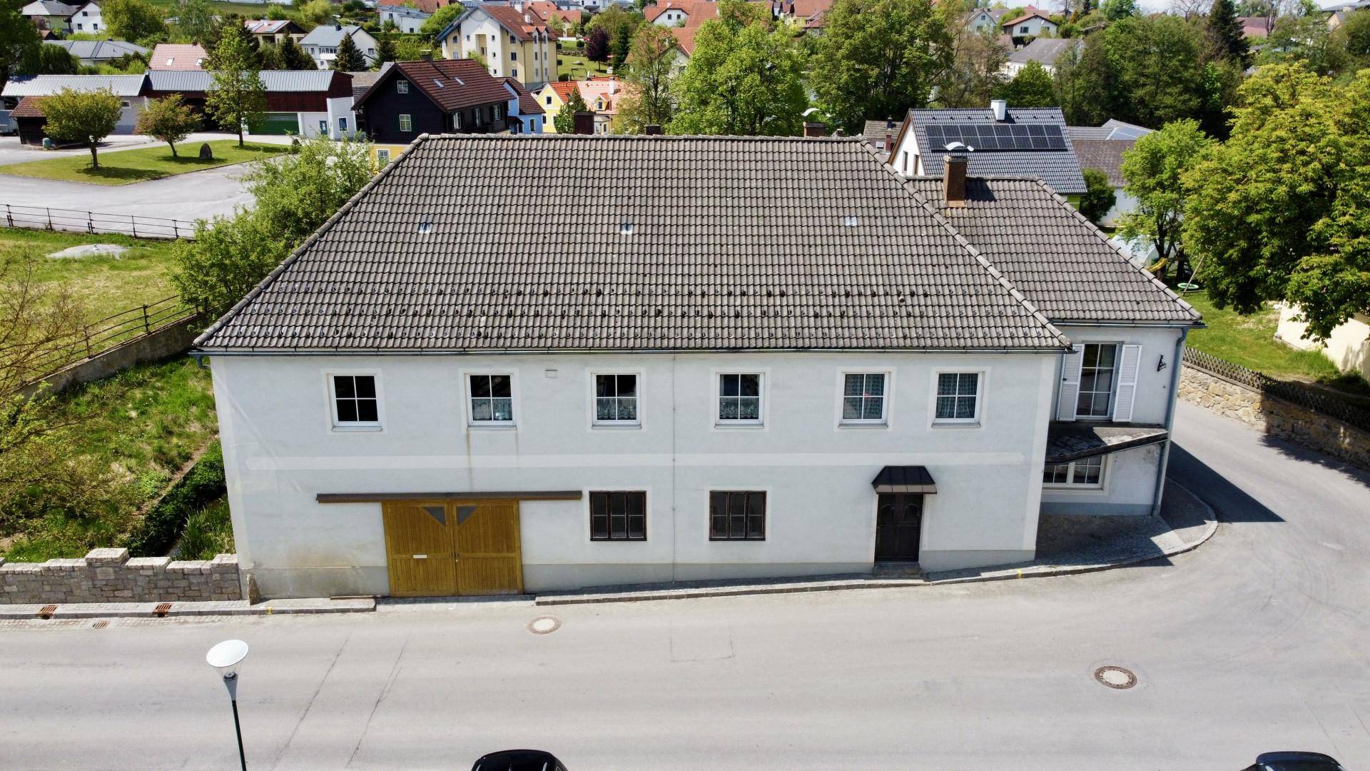 Luftaufnahme eines traditionellen Gebäudes mit Ziegeldach, umgeben von einer ländlichen Wohnsiedlung.
