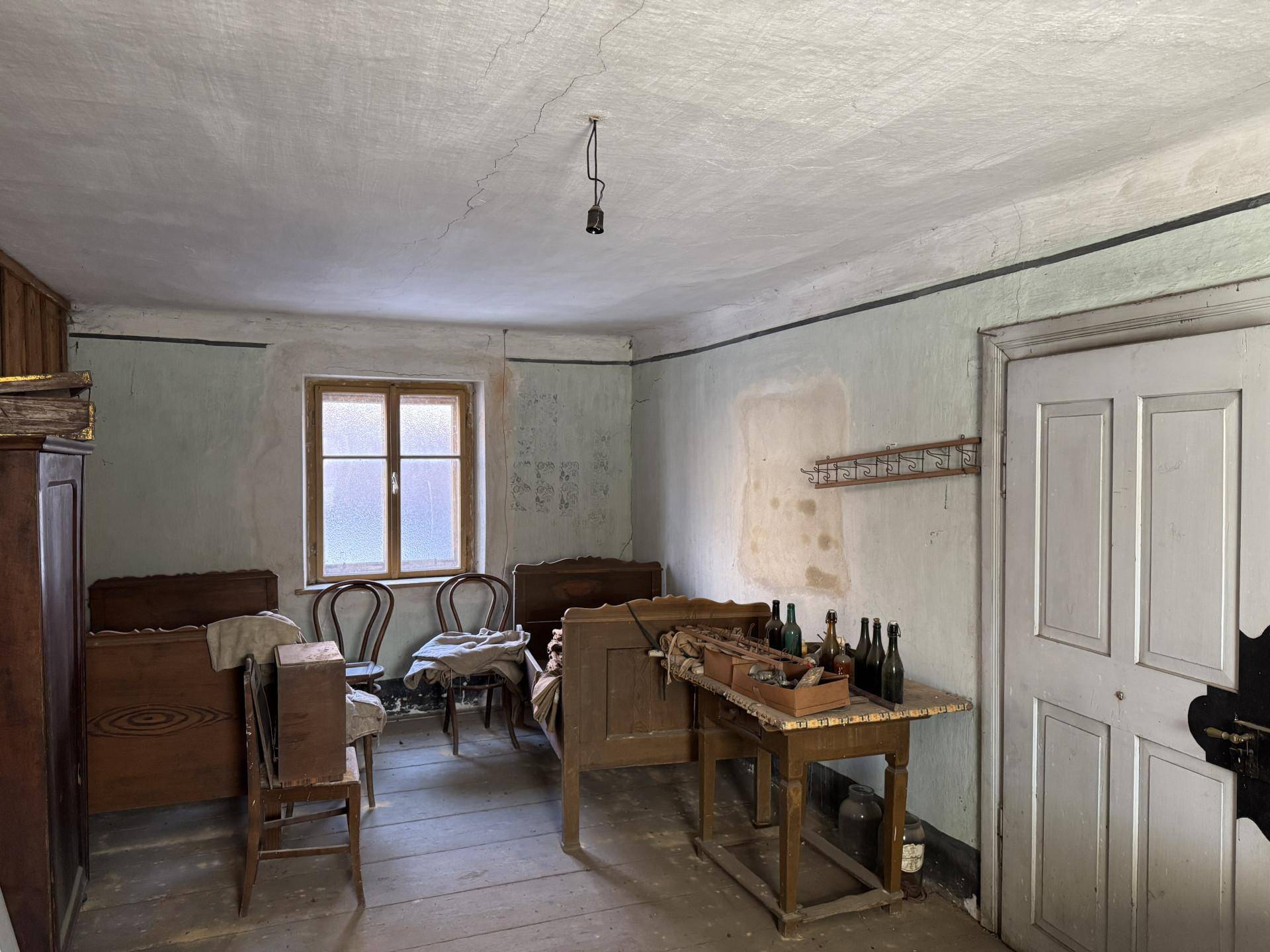 Schlafzimmer mit zwei alten Holzbetten, Holzdielenboden und hellblauen Wänden.