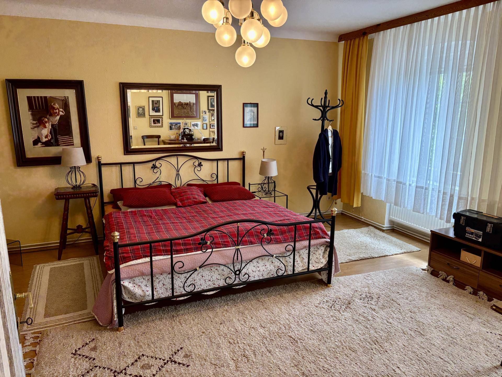 Geräumiges Schlafzimmer mit schmiedeeisernem Bett, gelben Wänden und Holzboden.
