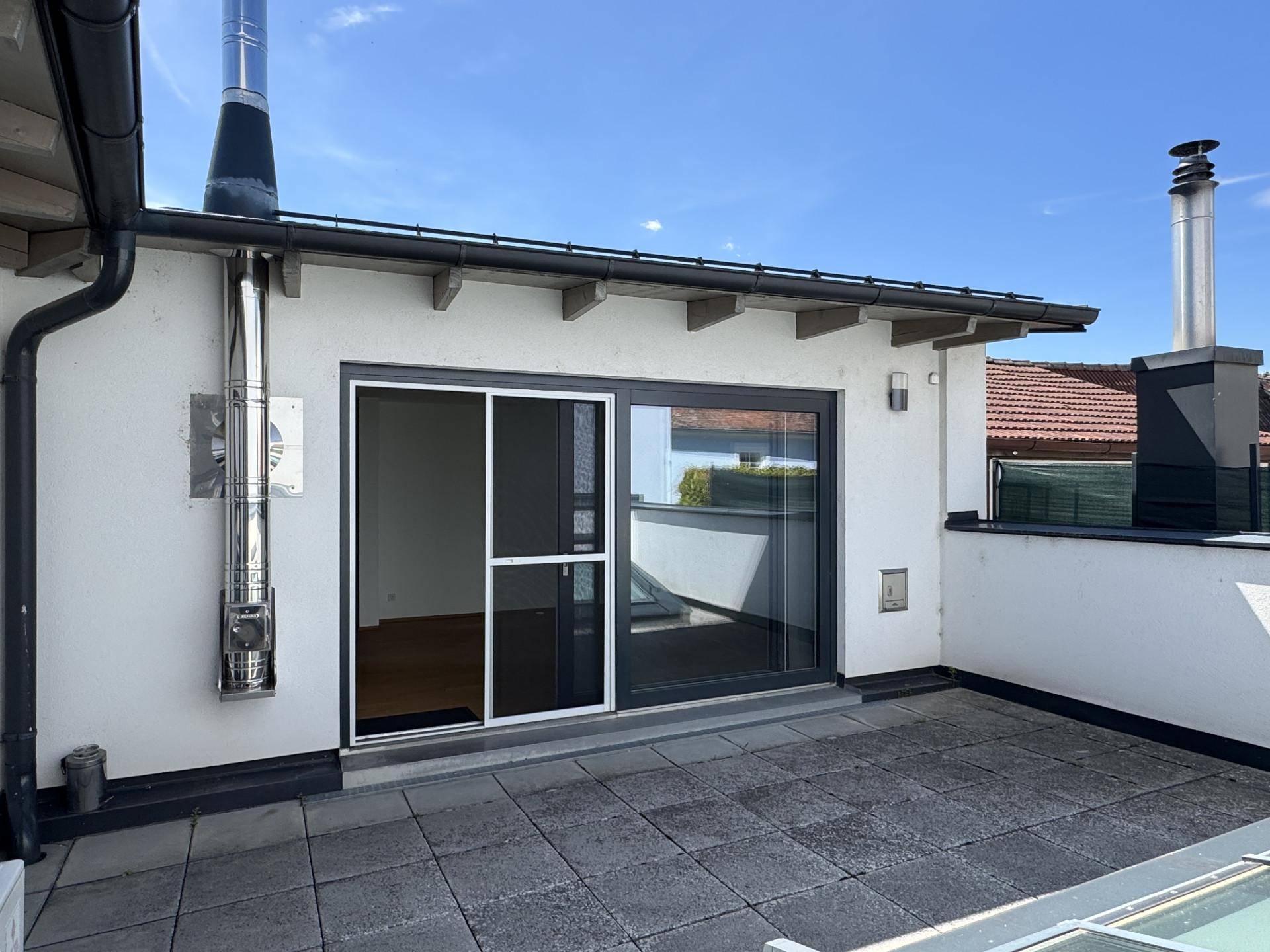 Geräumige Dachterrasse mit Fliesenboden und Schiebetürzugang zu den Innenräumen.