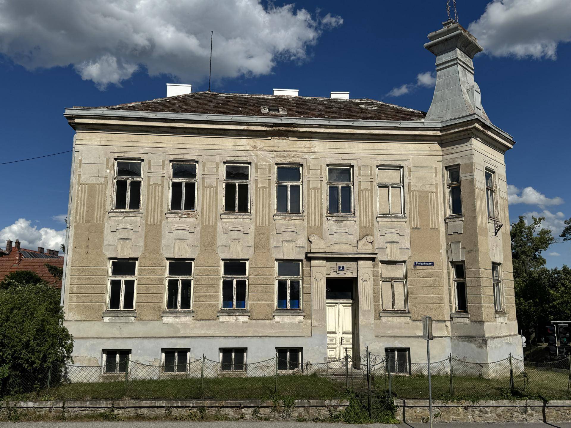 Frontansicht eines historischen Gebäudes mit symmetrischer Fassade und dekorativen Elementen.