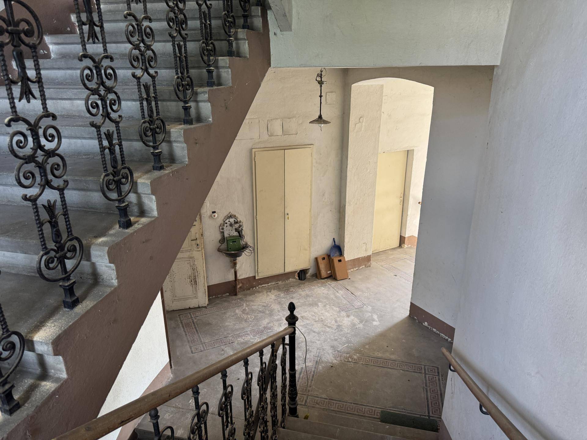 Historisches Treppenhaus mit schmiedeeisernem Geländer und originalen Fliesenböden.