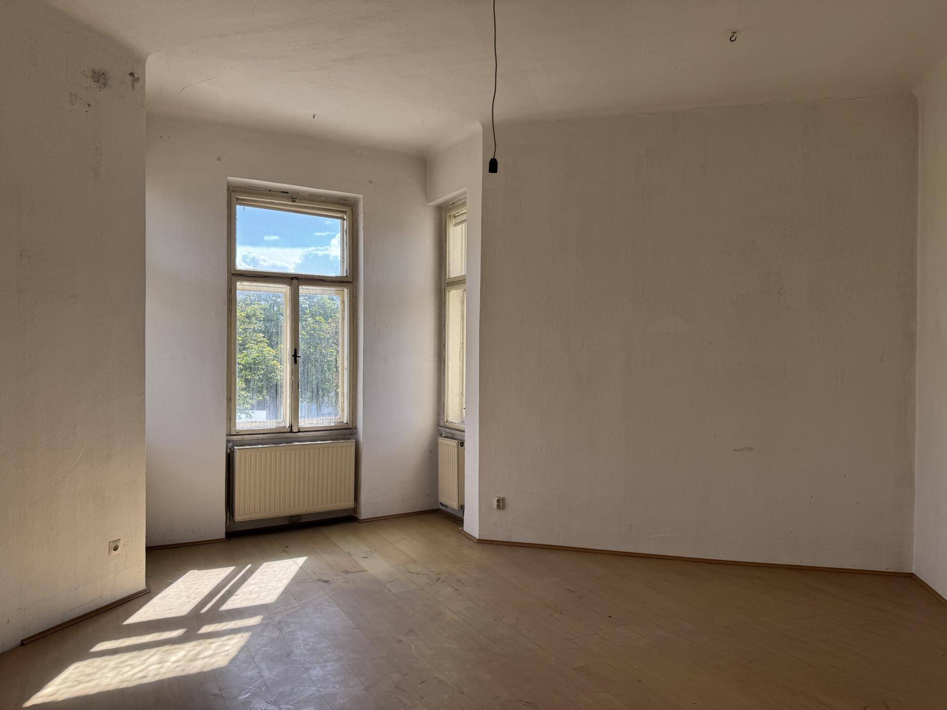 Helles Zimmer mit Holzboden, hohen Fenstern und viel Tageslicht.
