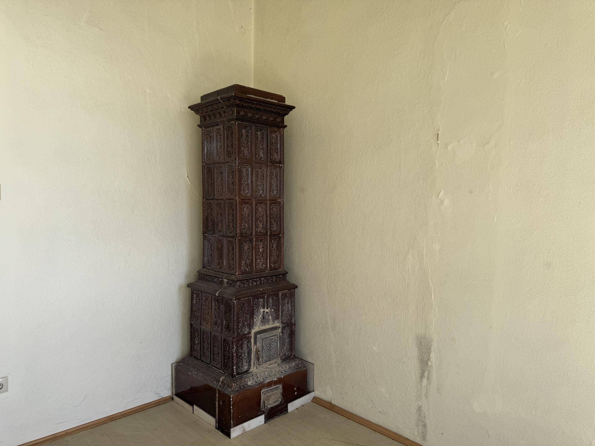 Traditioneller Kachelofen in einer Ecke des Zimmers, ein historisches Heizelement.