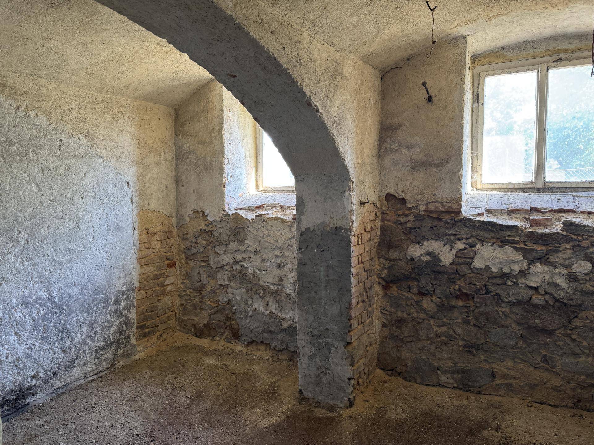 Rustikaler Kellerraum mit freiliegenden Ziegelwänden und kleinen Fenstern.