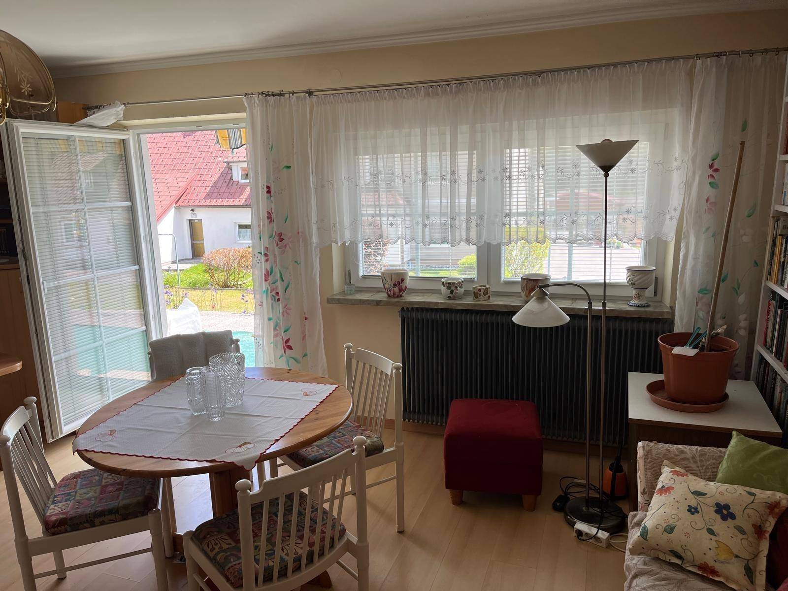 Essbereich im Wohnzimmer mit Holztisch, Stühlen und Blick durch die Fenster ins Grüne.