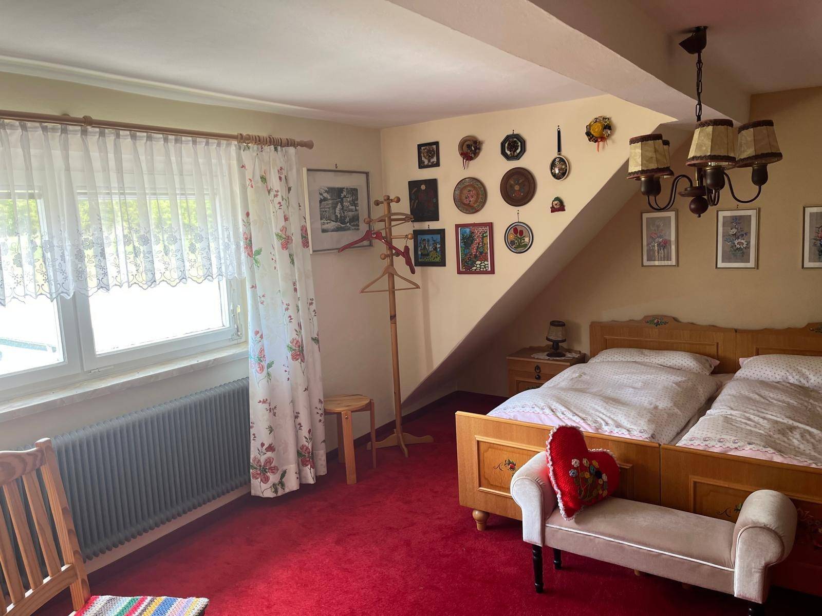 Schlafzimmer mit zwei Einzelbetten, rotem Teppich und Dachschräge, gemütlich eingerichtet.