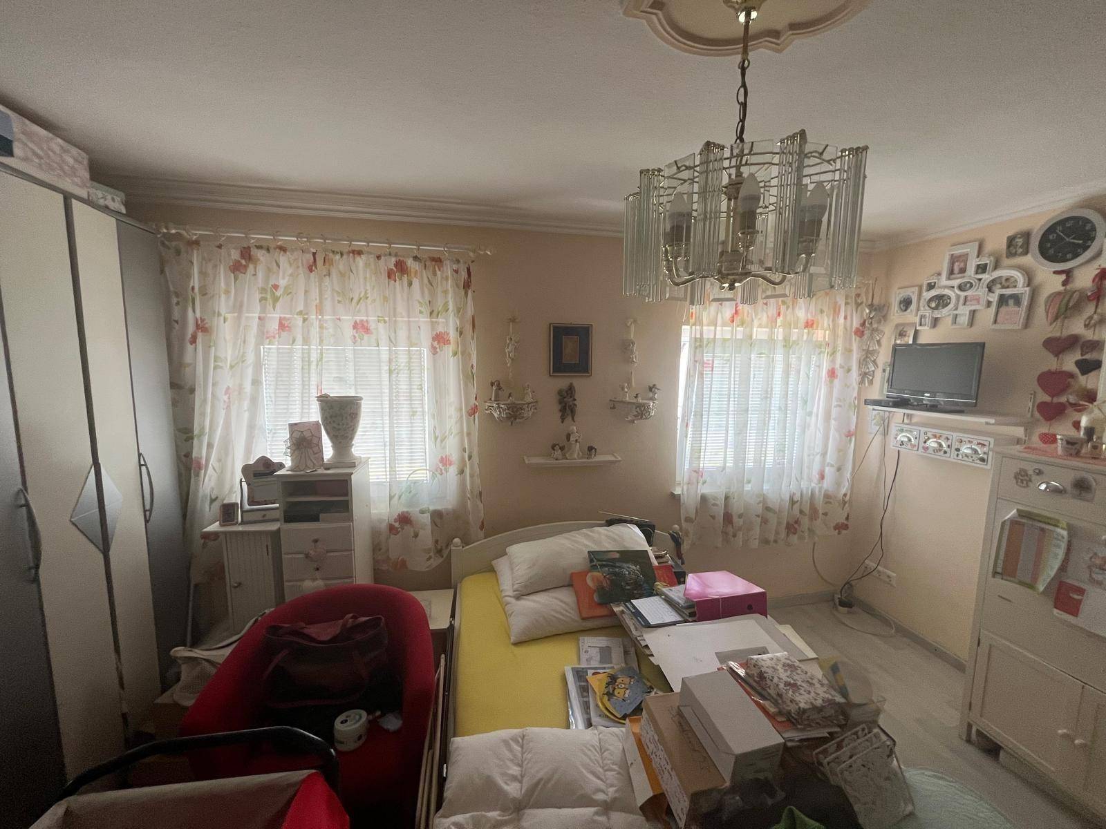 Helles Schlafzimmer mit Einzelbett, Kleiderschrank und zwei Fenstern, freundlich gestaltet.