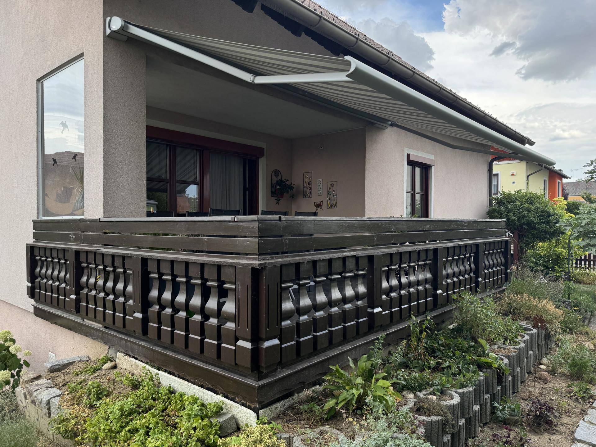 Überdachte Terrasse mit Markise und Blick auf den Garten.