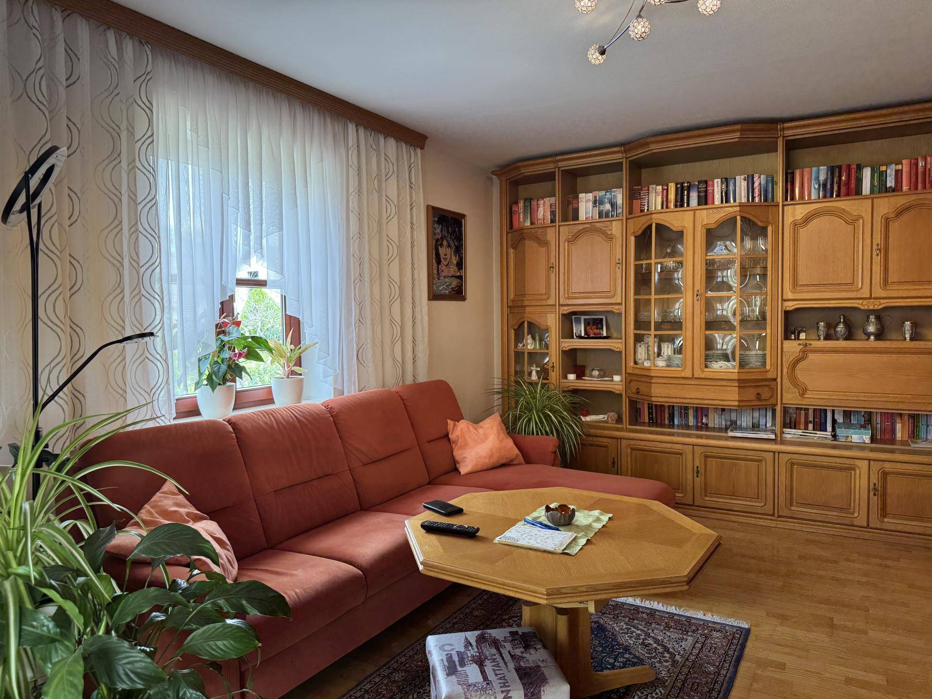 Gemütliches Wohnzimmer mit großem Sofa, Holzmöbeln und Bücherregal.