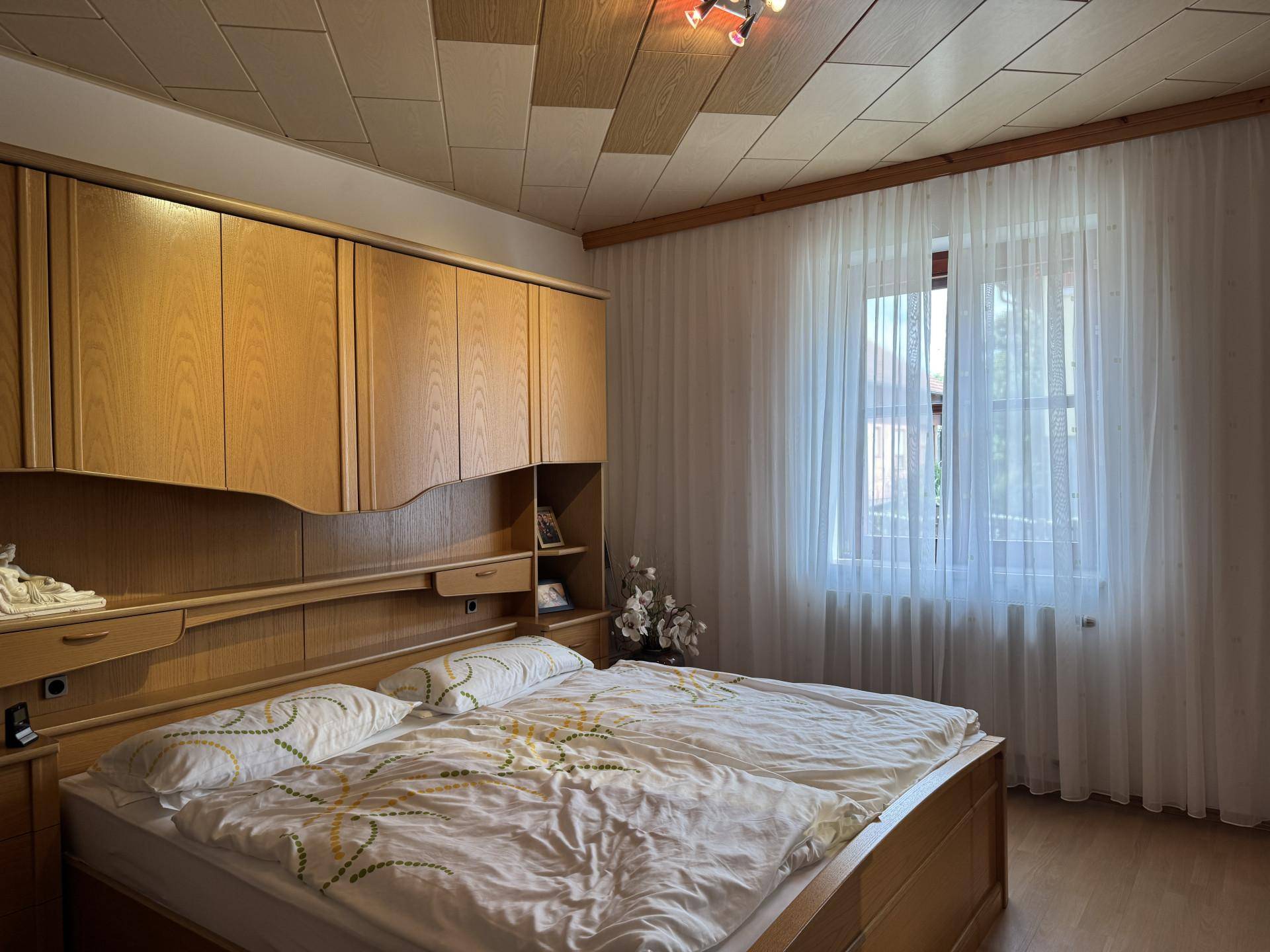 Schlafzimmer mit Einbauschränken, Doppelbett und Holzdeckenpaneelen.