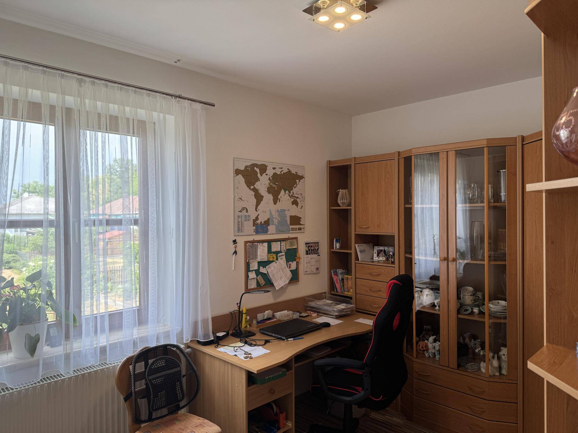 Helles Arbeitszimmer mit Schreibtisch, Holzregalen und großem Fenster.