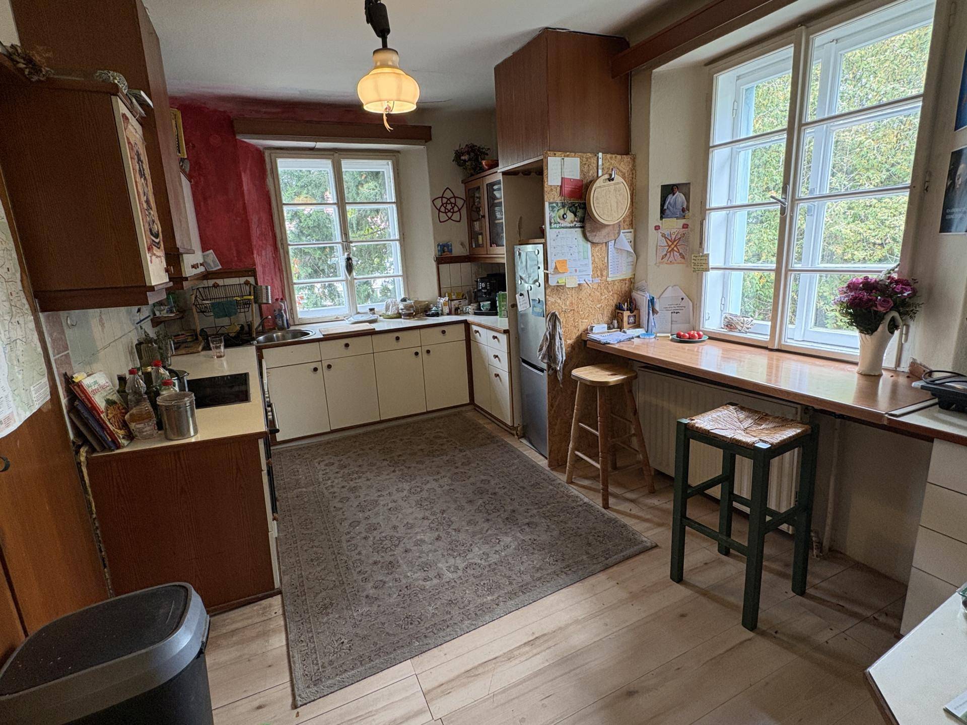 Rustikale Küche mit Holzboden, weißen Schränken und einem Arbeitsbereich am Fenster.