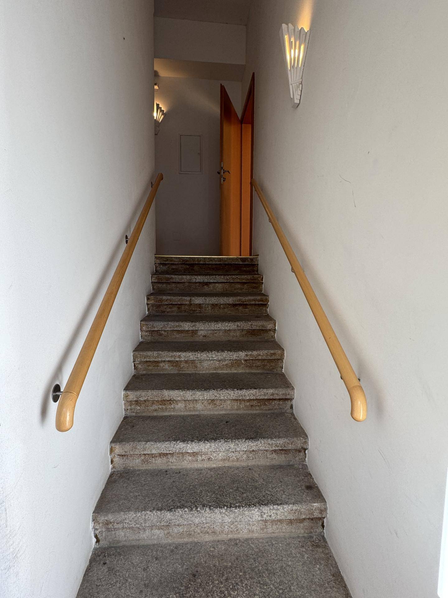 Steinerne Treppe mit Holzhandläufen, die in ein oberes Stockwerk führt, in gutem Zustand.